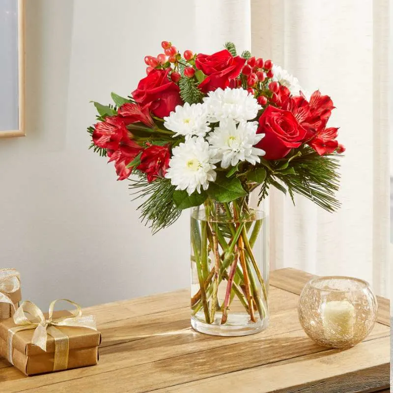 wooden tablescape featuring red and white bouquet inside a clear vase